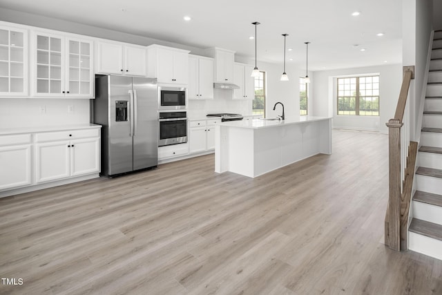 kitchen with pendant lighting, sink, appliances with stainless steel finishes, an island with sink, and white cabinets