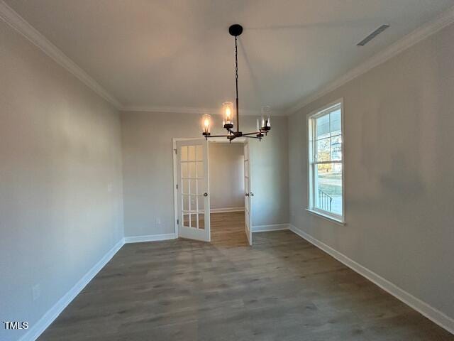 unfurnished dining area featuring wood-type flooring, an inviting chandelier, french doors, and crown molding