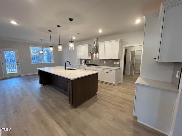 kitchen featuring white cabinets, a center island with sink, light wood-type flooring, and sink