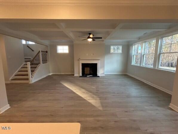 unfurnished living room with hardwood / wood-style flooring, a healthy amount of sunlight, beamed ceiling, and coffered ceiling