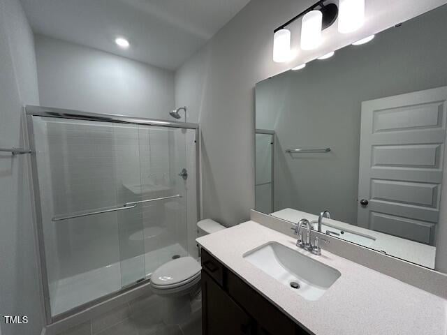 bathroom with tile patterned floors, vanity, toilet, and a shower with door