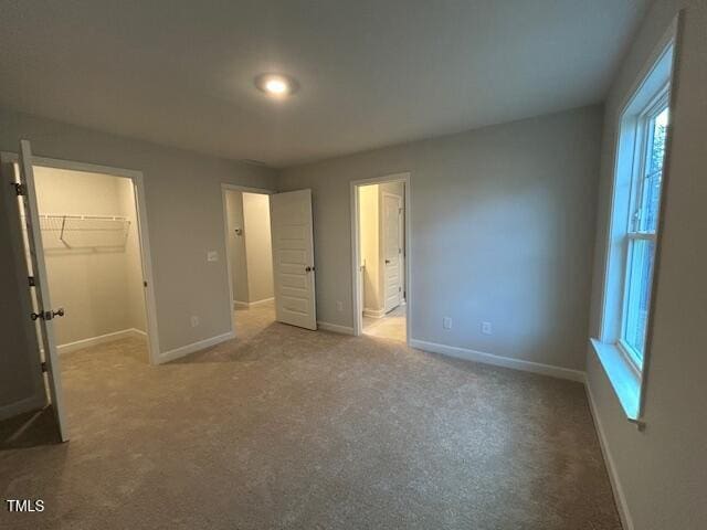 unfurnished bedroom featuring carpet flooring, connected bathroom, a spacious closet, and a closet