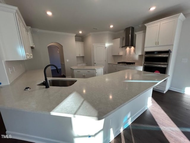 kitchen featuring white cabinets, a center island, and wall chimney range hood