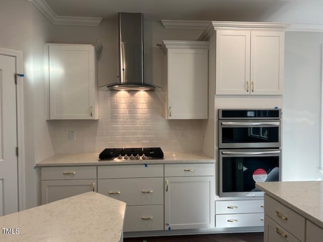 kitchen featuring white cabinets, appliances with stainless steel finishes, crown molding, and wall chimney range hood