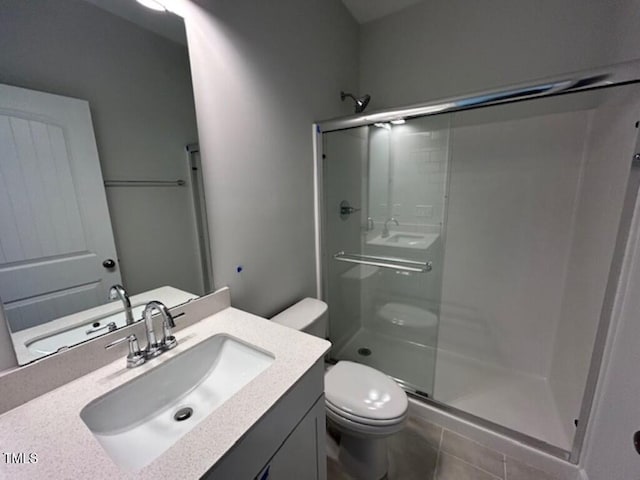 bathroom featuring tile patterned floors, vanity, toilet, and a shower with shower door