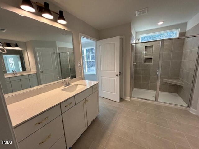 bathroom featuring a shower with door, vanity, a healthy amount of sunlight, and tile patterned flooring