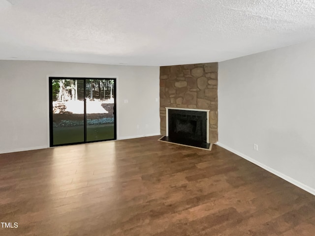 unfurnished living room featuring a textured ceiling, a stone fireplace, and wood-type flooring