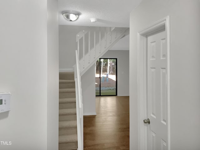 corridor with hardwood / wood-style flooring and a textured ceiling