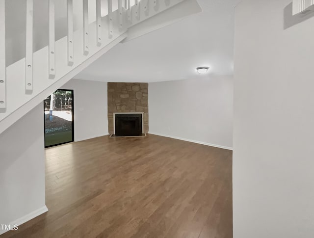 unfurnished living room featuring a stone fireplace and wood-type flooring