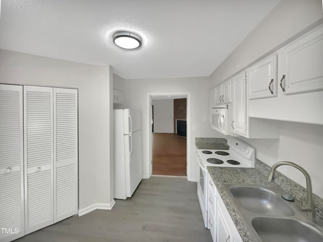 kitchen featuring hardwood / wood-style flooring, white cabinets, sink, and white appliances