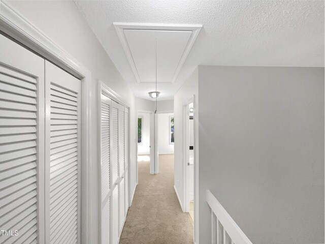 hall with a textured ceiling and light carpet