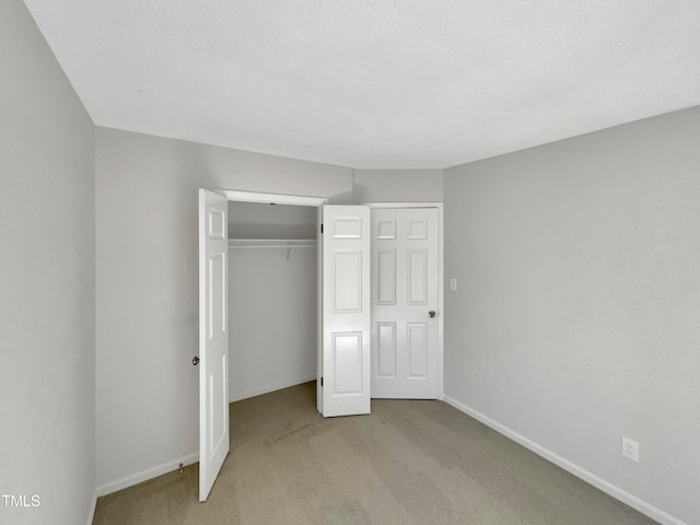 unfurnished bedroom with a closet and light carpet