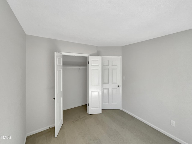 unfurnished bedroom with a closet and light colored carpet