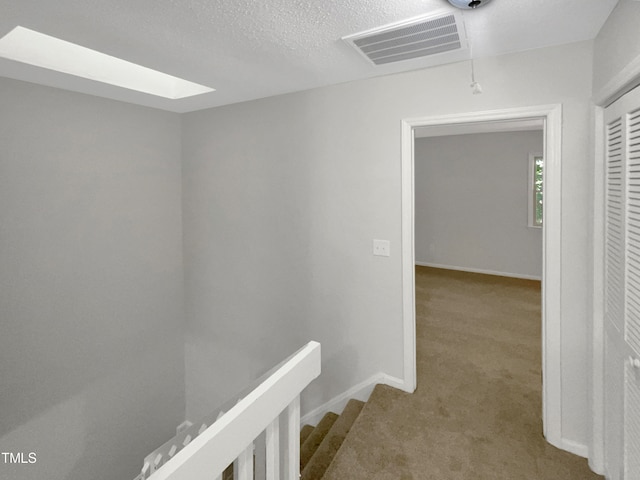 hallway featuring carpet flooring and a textured ceiling