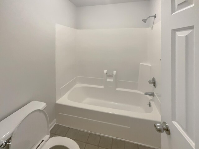 bathroom featuring tile patterned flooring, tub / shower combination, and toilet