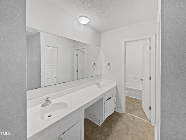 bathroom featuring a sink, double vanity, a textured ceiling, and a bath