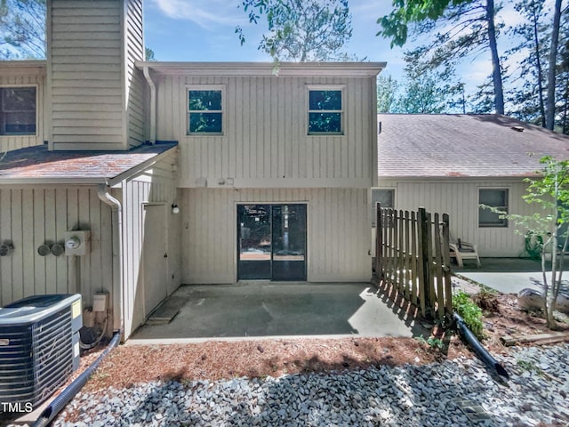 exterior space featuring central AC unit, a patio area, a shingled roof, and a chimney