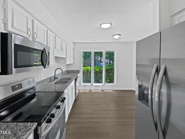 kitchen with a sink, dark wood-style flooring, white cabinetry, and appliances with stainless steel finishes