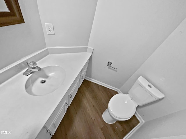 bathroom featuring toilet, baseboards, vanity, and wood finished floors