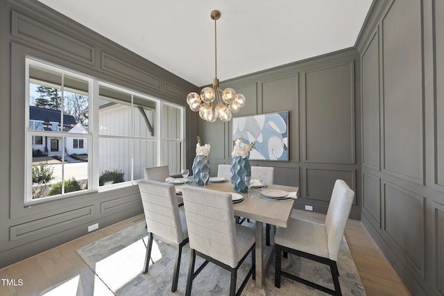 dining room with a decorative wall, a notable chandelier, and wood finished floors