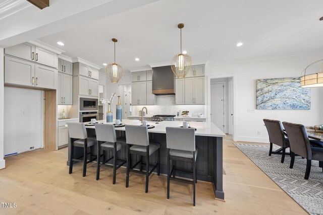 kitchen featuring premium range hood, light countertops, appliances with stainless steel finishes, and ornamental molding