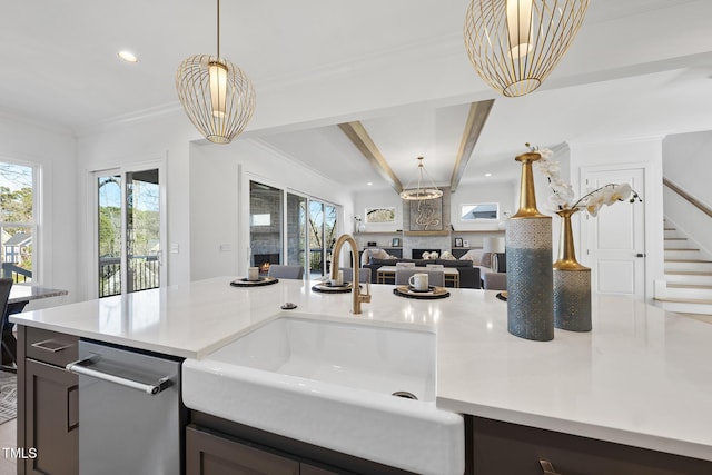 kitchen with crown molding, a sink, open floor plan, light countertops, and pendant lighting