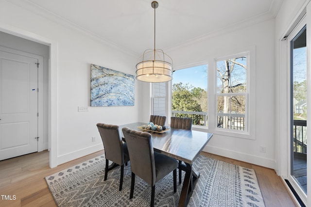 dining room with ornamental molding, light wood-style flooring, and baseboards