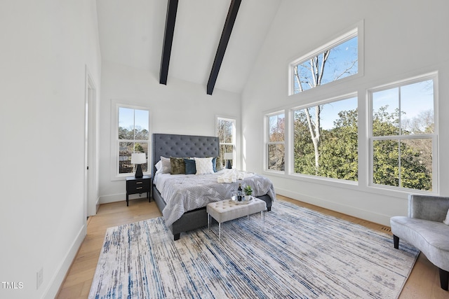 bedroom featuring high vaulted ceiling, light wood finished floors, beam ceiling, and baseboards