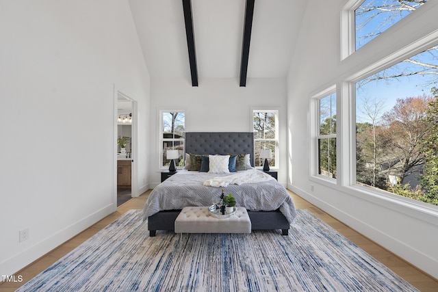 bedroom featuring ensuite bath, baseboards, high vaulted ceiling, and beam ceiling