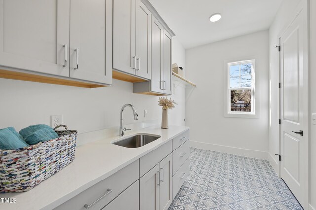 kitchen featuring light countertops, a sink, and baseboards