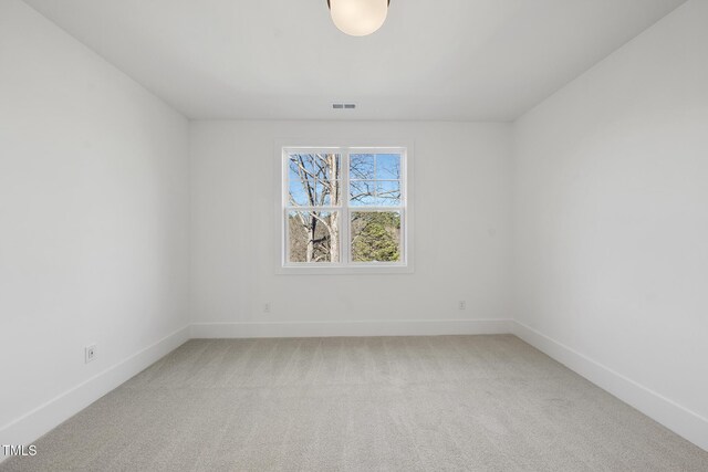 spare room featuring visible vents, light carpet, and baseboards