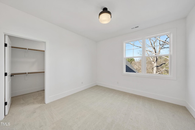 unfurnished bedroom with light carpet, visible vents, baseboards, a closet, and a walk in closet