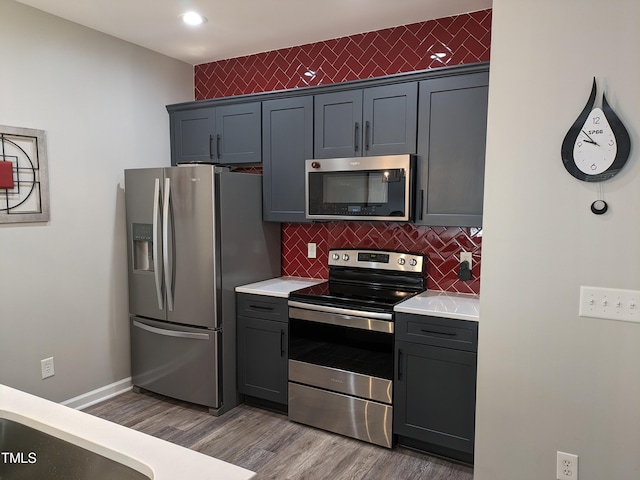 kitchen featuring tasteful backsplash, light hardwood / wood-style flooring, gray cabinets, and stainless steel appliances