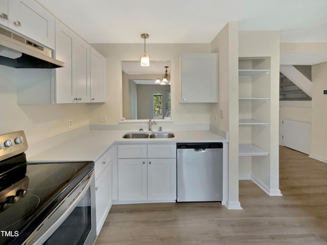 kitchen with appliances with stainless steel finishes, white cabinetry, pendant lighting, light wood-type flooring, and sink