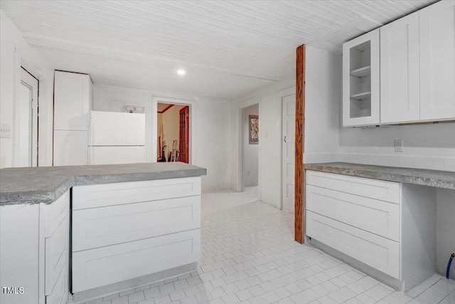 kitchen featuring light tile patterned floors, white refrigerator, and white cabinetry