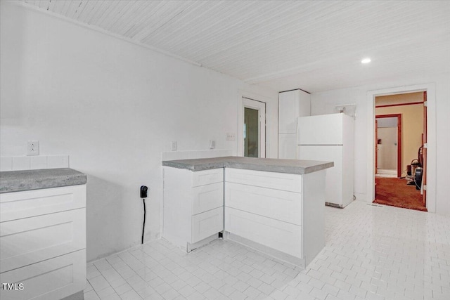 kitchen featuring white refrigerator, white cabinetry, and light tile patterned floors