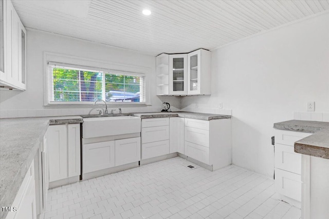 kitchen with white cabinets, sink, and light tile patterned flooring