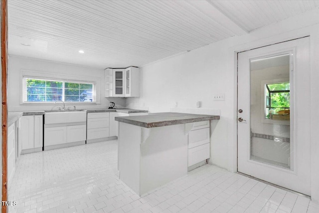 kitchen featuring sink, kitchen peninsula, light tile patterned floors, and white cabinets