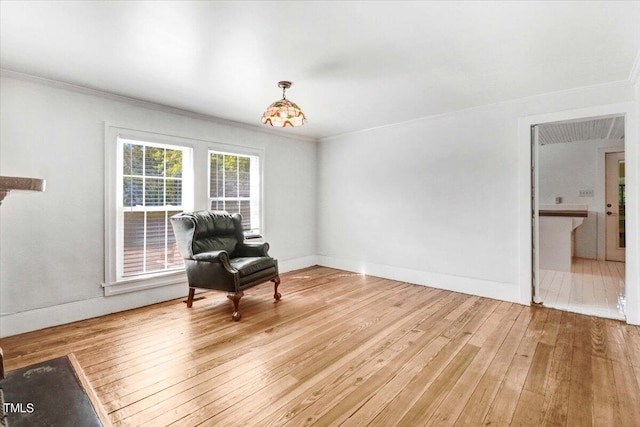 sitting room featuring light wood-type flooring, crown molding, and a chandelier