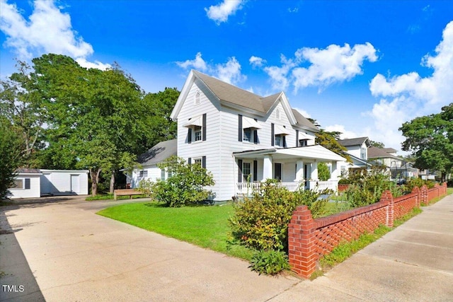 view of side of home with an outdoor structure, a lawn, and covered porch