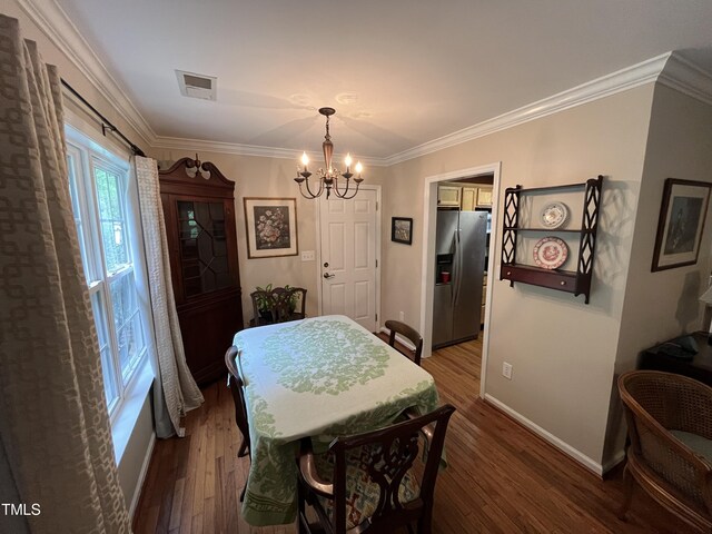 dining room with hardwood / wood-style flooring, a notable chandelier, and ornamental molding