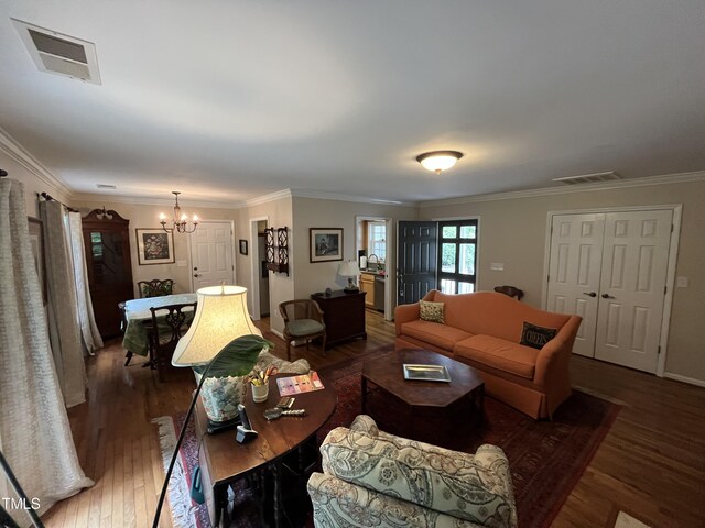 living room with an inviting chandelier, ornamental molding, and dark hardwood / wood-style flooring