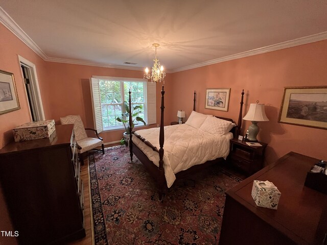 bedroom with crown molding, an inviting chandelier, and hardwood / wood-style flooring