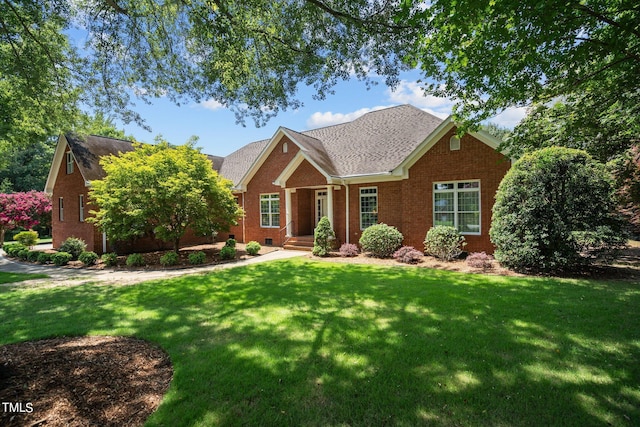 craftsman-style house with crawl space, a shingled roof, a front yard, and brick siding