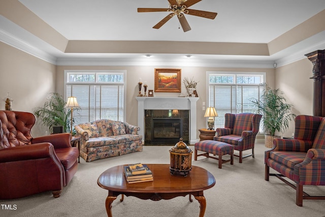 living area with light carpet, a tray ceiling, crown molding, and a tile fireplace