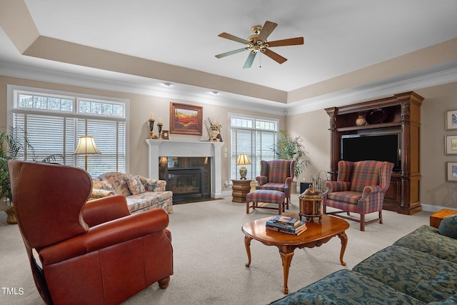 living room featuring ornamental molding, a tray ceiling, a tiled fireplace, and light colored carpet