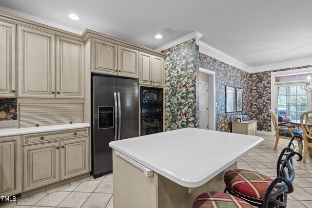 kitchen with a center island, light countertops, black appliances, and wallpapered walls