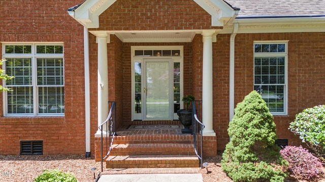 entrance to property featuring roof with shingles, brick siding, crawl space, and visible vents