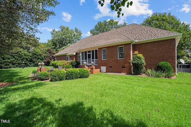 rear view of property with crawl space, brick siding, a yard, and roof with shingles