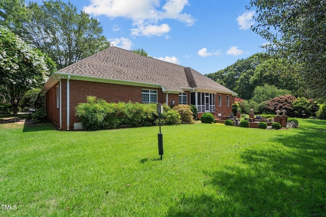 view of front of property featuring a shingled roof, brick siding, and a front lawn